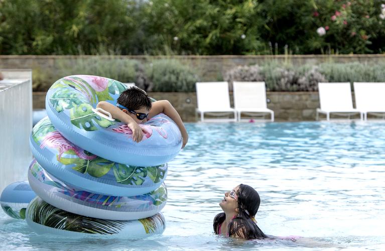 Bambini giocano in piscina con salvagenti colorati.